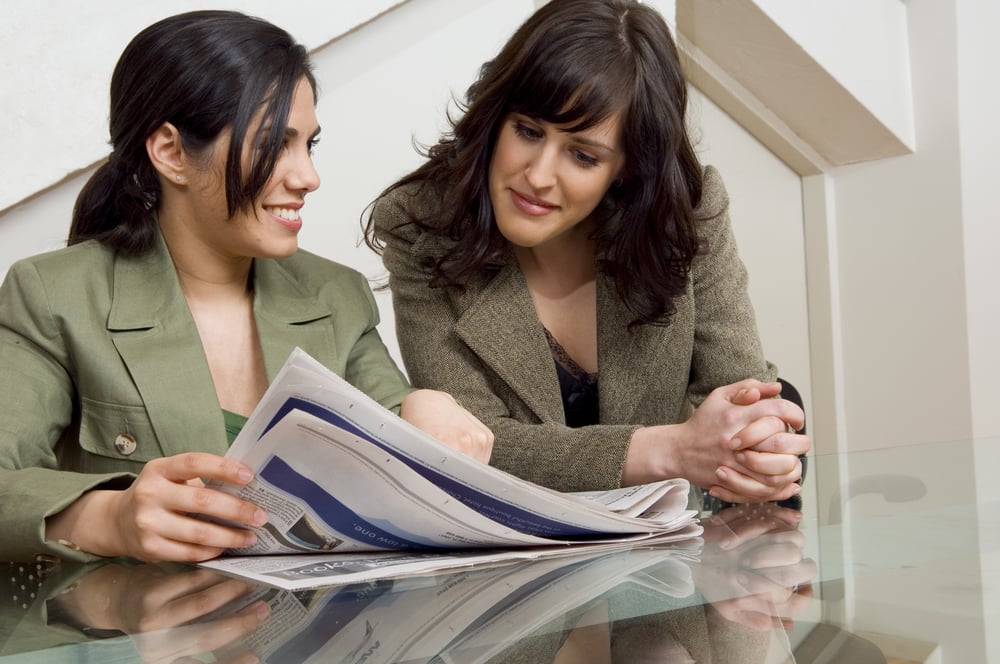 Businesswomen looking at a newspaper